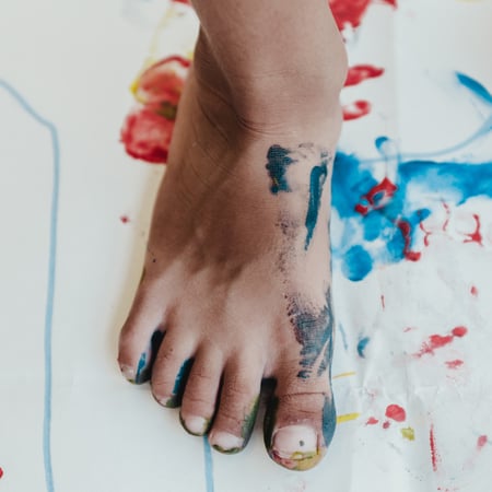 Child foot with finger paint on paper