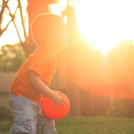 child ready to throw large orange ball